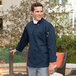 A man wearing a Uncommon Chef navy blue long sleeve chef coat.