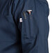 A close up of an Uncommon Chef navy long sleeve chef coat with pockets.