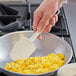 A hand holding a Vollrath SoftSpoon spatula over scrambled eggs.