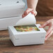 A hand opening a Bio-Pak white paper take-out container with a window