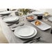 An American Metalcraft matte white round coupe melamine plate on a table with food and a glass of water.