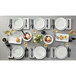 A table set with a rectangular matte white American Metalcraft melamine platter, white plates, and silverware.