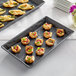 An American Metalcraft black faux slate rectangular melamine platter holding a trays of food on a table.