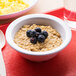 A white Carlisle Kingline nappie bowl filled with oatmeal and blueberries on a red tray.