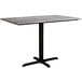 A Lancaster Table & Seating rectangular dining table with a textured gray top and black cross base.