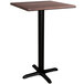 A Lancaster Table & Seating square counter height table with a walnut top and black base plate.