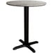 A Lancaster Table & Seating round dining table with a textured concrete top and cross base plate.