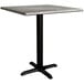 A Lancaster Table & Seating square dining height table with a textured gray top and black cross base.