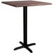 A Lancaster Table & Seating square counter height table with a textured walnut top and black cross base.