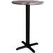 A round Lancaster Table & Seating counter height table with a black cross base.