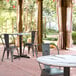 A Lancaster Table & Seating Excalibur round table with chairs on a brick patio.