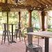 A Lancaster Table & Seating bar height table with a textured mixed plank finish on a patio with chairs.