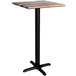 A Lancaster Table & Seating bar height table with a black cross base and a wooden top.