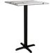 A Lancaster Table & Seating bar height table with a white marble top and a cross base plate.