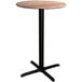 A Lancaster Table & Seating round bar height table with a textured Yukon Oak top and black cross base.