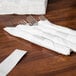 A group of white paper napkins wrapped with white self-adhering paper bands.