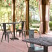 A Lancaster Table & Seating square table with a smooth finish and cross base plate on an outdoor patio with chairs.