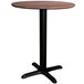 A Lancaster Table & Seating Excalibur round dining table with a textured walnut top and black base.