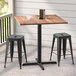 A Lancaster Table & Seating Excalibur counter height table with two stools on a porch.