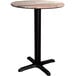 A Lancaster Table & Seating round wooden table with a black cross base.
