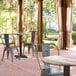 A Lancaster Table & Seating Excalibur round dining table and chairs on an outdoor patio.