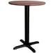 A round Lancaster Table & Seating dining table with a textured walnut top and black cross base.
