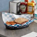 Blue check deli wrap paper on a table with a sandwich and fries in a basket.