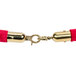 A red velvet rope with brass ends on a gold chain.
