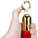 A hand holding a gold and red Aarco stanchion rope end.