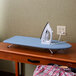 A Wood Table Top Ironing Board with an iron on it.