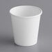 A white paper cup with a white rim on a gray surface.