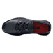 A black Shoes For Crews Karina women's athletic shoe with laces and a red sole.