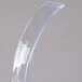 A close-up of a clear plastic curved ladle.