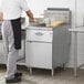 A man cooking fries in a Main Street Equipment stainless steel floor fryer in a commercial kitchen.