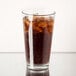 A Libbey rim tempered mixing glass filled with cola and ice on a table.