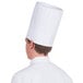 A person wearing a white Royal Paper pleated chef hat.