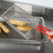 A person using a Grindmaster full size fryer basket to fry food.