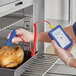 A person using a Comark Type-K Thermocouple Thermometer to measure the temperature of a chicken.