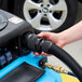 A hand using a black hose to clean a car with a Mytee Grand Prix extractor.