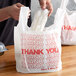 A man holding a white plastic bag with red "Thank You" text.