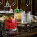 A tray with Luigi Bormioli Mixology Textures Rocks glasses filled with drinks on a table.
