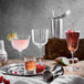 A table set with Luigi Bormioli Bach Champagne Flutes filled with red, brown, and pink liquids.