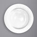 A close-up of a white International Tableware Dover porcelain pasta bowl with a wide rim.