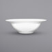 A close up of an International Tableware bright white porcelain grapefruit bowl with a rolled edge.