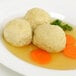 A plate of food with a few Golden Dipt matzoh meal dumplings in broth.