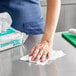 A woman cleaning a hospital cafeteria counter with a WipesPlus disinfecting wipe.