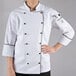A woman wearing a white Chef Revival chef's coat with black piping.