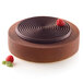 A chocolate cake baked in a Silikomart Tourbillon silicone mold with raspberries on top.