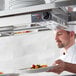A chef using a ServIt double strip warmer to hold a plate of food.