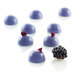 A group of purple chocolate domes with blackberries on a white surface.